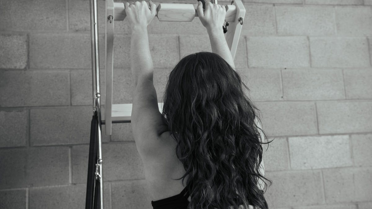 Focused woman practicing exercises at the best Pilates studio in West Hollywood, skillfully using a Contrology tower (designed by Joe Pilates himself) for a balanced workout, representing the high-quality training provided at our LA Pilates studio.