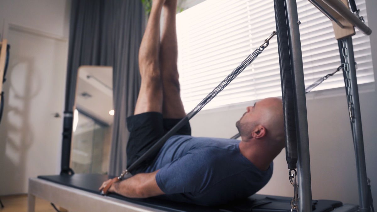 Pushing the boundaries of traditional Pilates at our top-rated LA Pilates studio, a connected man engaged in "Double Straight Leg Stretch"on a Contrology tower.