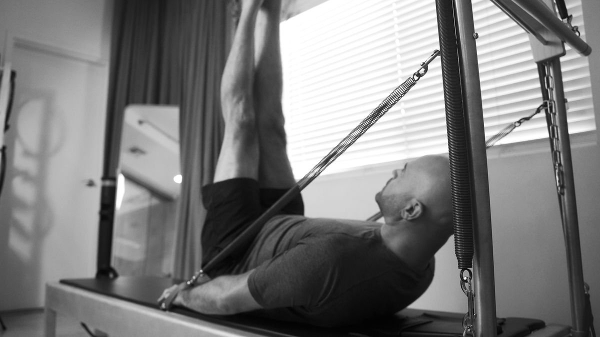 Expert guidance and individualized training at our LA Pilates Studio, man skillfully working on "Double Straight Leg Stretch" on a Contrology tower.
