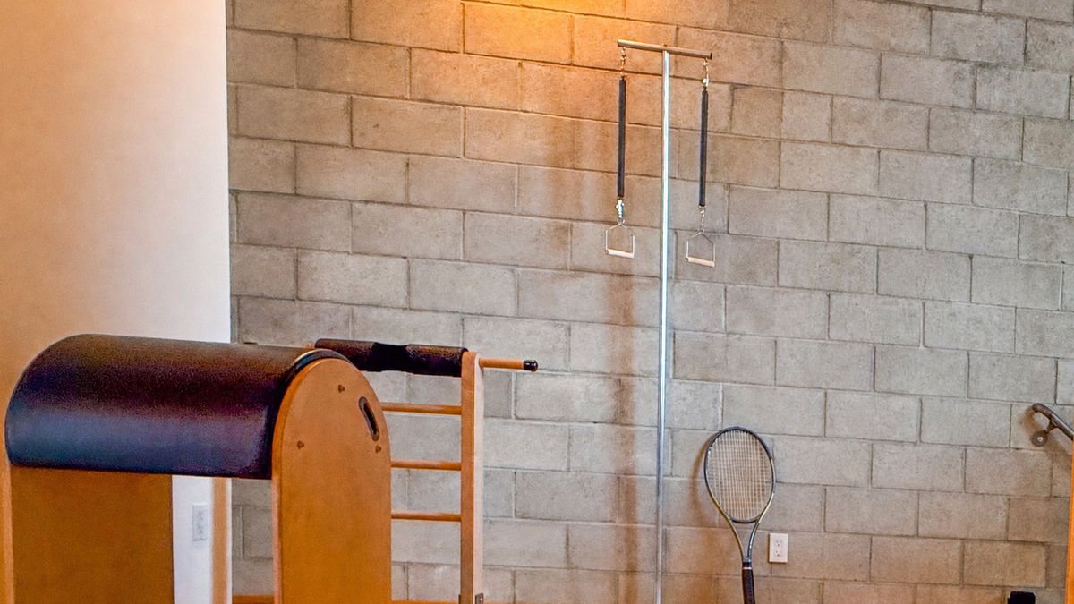 A Ped-o-Pul, the standing spring apparatus, against the cinder-block wall of the West Hollywood Pilates studio, with a tennis racquet leaning beside it
