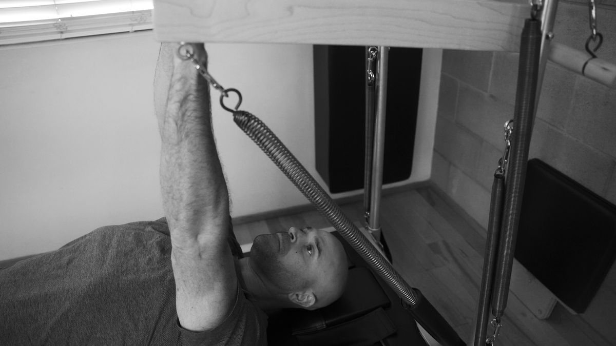 Perfecting functional movement: a dedicated man using a Push Through Bar on the Contrology tower during his Pilates practice, at our exceptional West Hollywood Pilates studio.