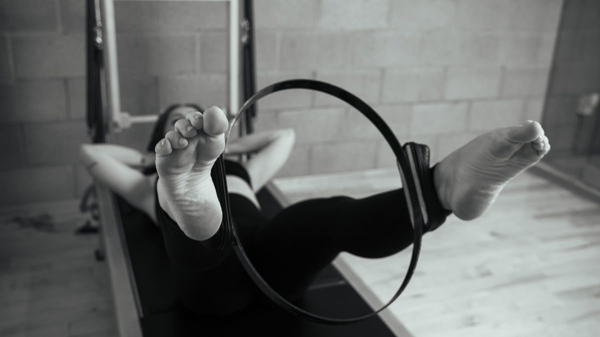 Pilates West Hollywood-style, an engaged woman strengthening her body using the magic circle on a Contrology tower in our state-of-the-art Pilates studio