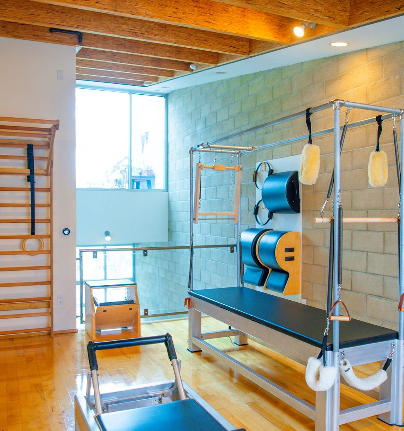 Cadillac trapeze table with hanging straps and fleece loops, wooden wall bars behind